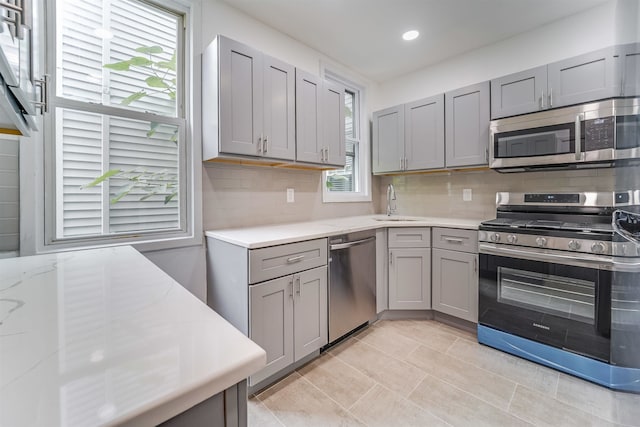 kitchen featuring gray cabinetry, decorative backsplash, and stainless steel appliances