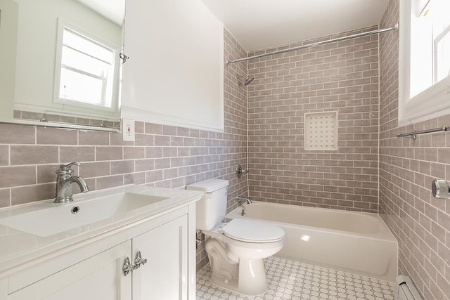 full bathroom featuring vanity, a baseboard heating unit, tile patterned flooring, tiled shower / bath combo, and tile walls