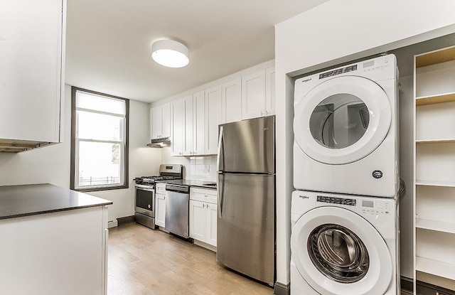 clothes washing area featuring a baseboard heating unit, light hardwood / wood-style flooring, and stacked washer and clothes dryer