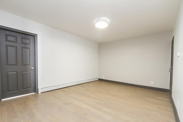 empty room with light hardwood / wood-style flooring and a baseboard heating unit