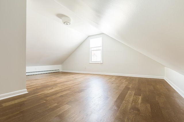 additional living space featuring dark hardwood / wood-style flooring, lofted ceiling, and a baseboard heating unit