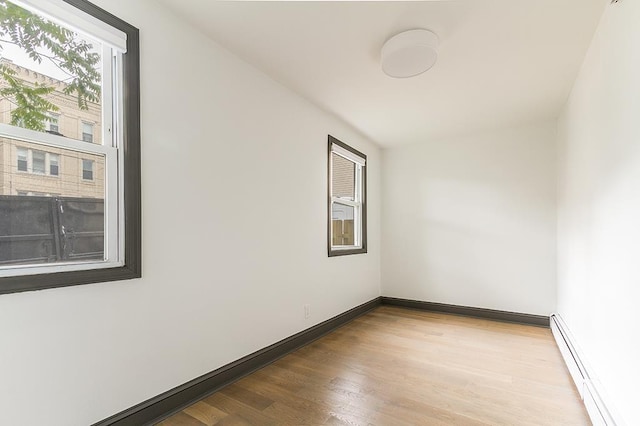 empty room with a baseboard radiator and light hardwood / wood-style floors