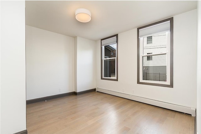 empty room featuring light wood-type flooring and baseboard heating