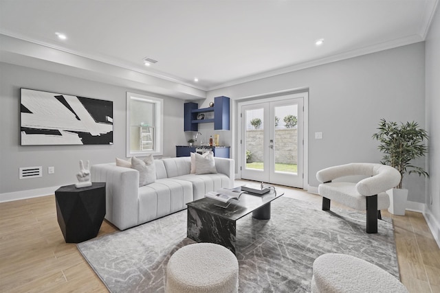 living room featuring light hardwood / wood-style floors, french doors, ornamental molding, and bar area