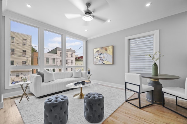 living room featuring light wood-type flooring, ceiling fan, and crown molding