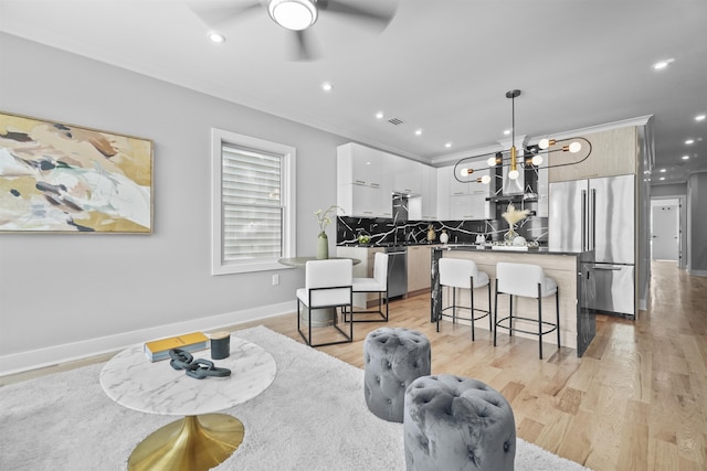 dining space featuring ceiling fan with notable chandelier, light hardwood / wood-style floors, ornamental molding, and sink