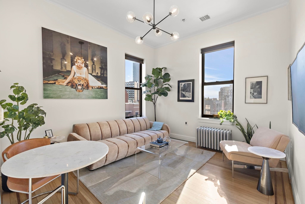 living room featuring radiator, a wealth of natural light, crown molding, and hardwood / wood-style floors