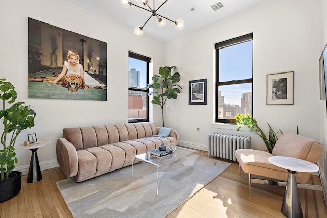 living room with radiator, a wealth of natural light, ornamental molding, and hardwood / wood-style floors