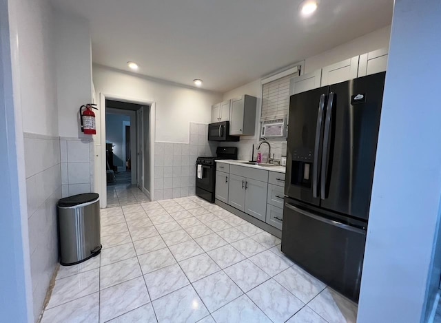 1611 71st St, North Bergen, NJ 07047 - kitchen featuring black appliances, tile walls, gray cabinetry, light countertops, and a wainscoted wall