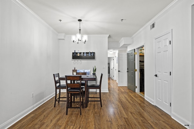 dining room featuring dark hardwood / wood-style floors, ornamental molding, and a notable chandelier