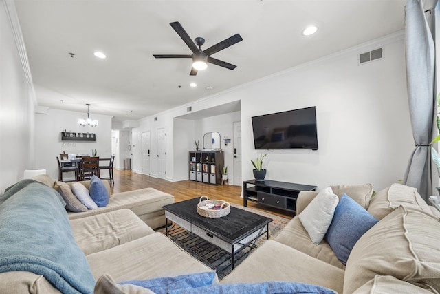 living room featuring wood-type flooring, ceiling fan with notable chandelier, and crown molding