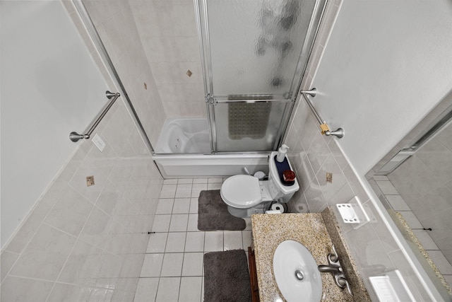 bathroom featuring tile patterned floors, tile walls, enclosed tub / shower combo, and vanity