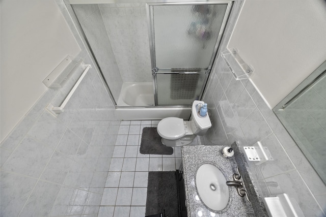 full bathroom featuring tile patterned flooring, vanity, bath / shower combo with glass door, tile walls, and toilet