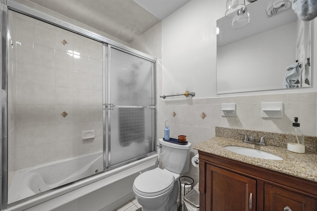 full bathroom featuring bath / shower combo with glass door, tile walls, toilet, and vanity