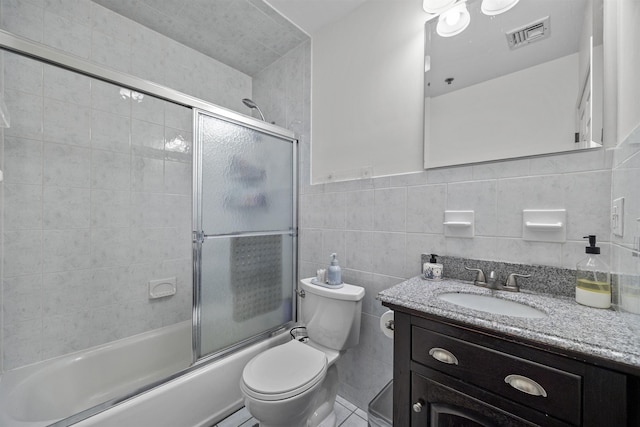 full bathroom featuring tile walls, toilet, vanity, and combined bath / shower with glass door