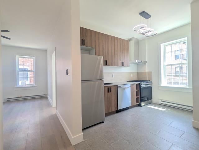 368 Palisade Ave, Jersey City, NJ 07307 - kitchen featuring freestanding refrigerator, stainless steel range with gas stovetop, wall chimney exhaust hood, baseboard heating, and dishwasher