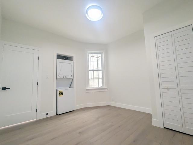368 Palisade Ave, Jersey City, NJ 07307 - unfurnished bedroom featuring stacked washer / drying machine, light wood-type flooring, and baseboards