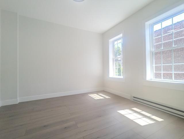 368 Palisade Ave, Jersey City, NJ 07307 - empty room with baseboard heating, wood finished floors, and baseboards