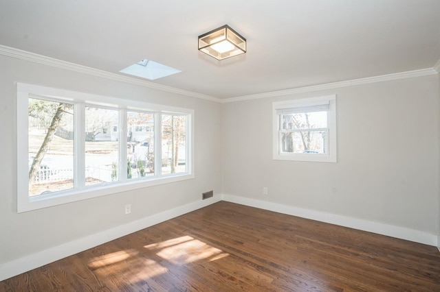 unfurnished room featuring baseboards, dark wood-type flooring, a skylight, and crown molding