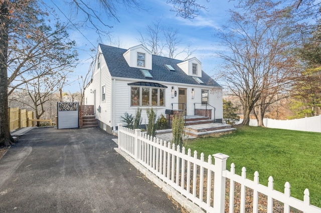 cape cod home featuring a fenced front yard, a front yard, and a shingled roof