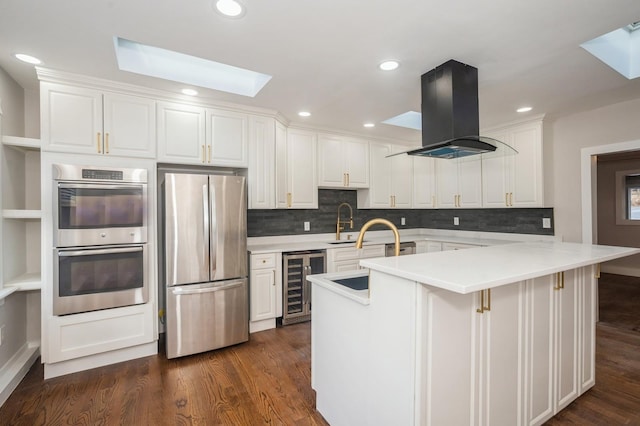 kitchen with beverage cooler, island exhaust hood, dark wood-style flooring, and stainless steel appliances