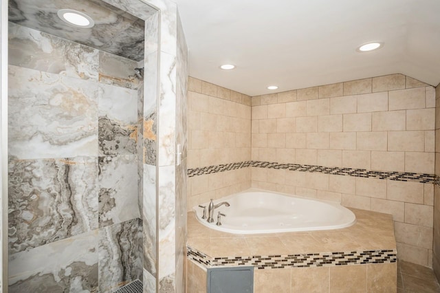 bathroom with recessed lighting, a bath, vaulted ceiling, and a tile shower