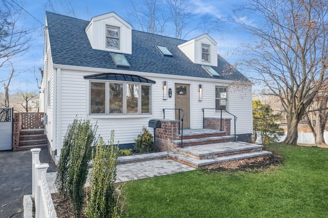 cape cod home with roof with shingles and a front lawn