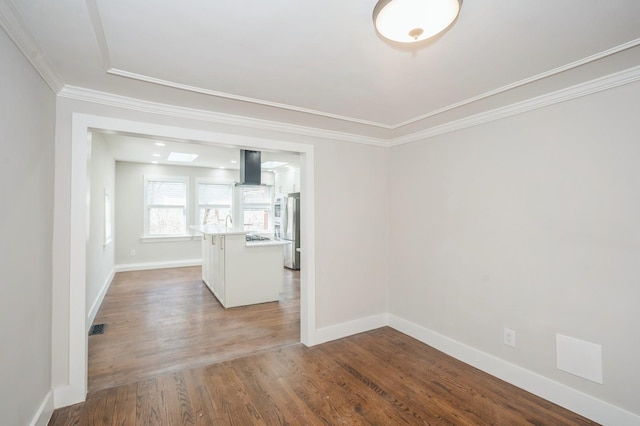 spare room with visible vents, ornamental molding, baseboards, and wood finished floors