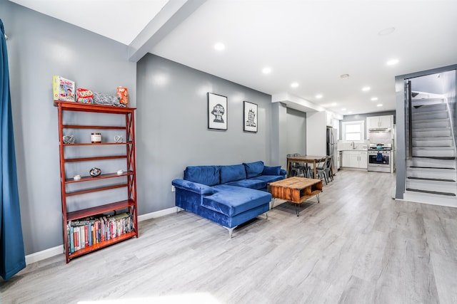 living room featuring recessed lighting, baseboards, light wood-style flooring, and stairway