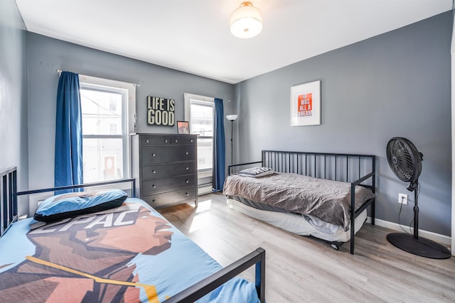 bedroom with baseboards, a baseboard heating unit, and wood finished floors