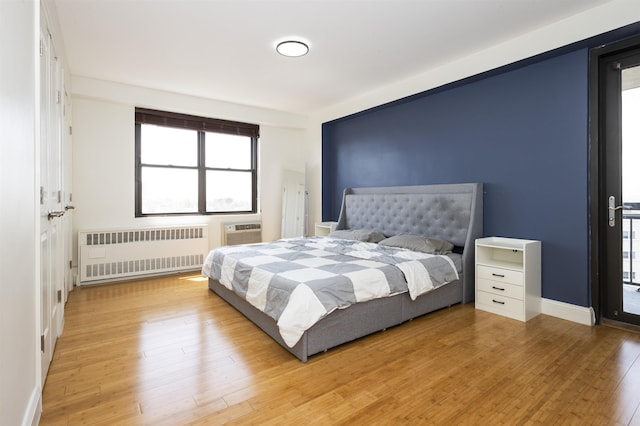 bedroom with multiple windows, light wood finished floors, and radiator