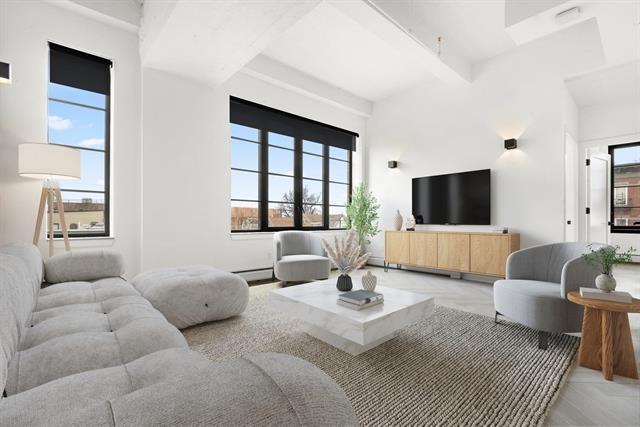 living area with beamed ceiling and baseboard heating