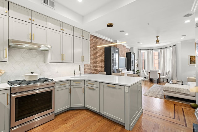 kitchen featuring visible vents, gray cabinetry, a sink, stainless steel range with gas cooktop, and under cabinet range hood
