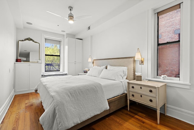 bedroom with visible vents, a ceiling fan, baseboards, and wood finished floors