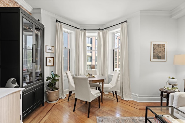 dining room with baseboards, ornamental molding, and light wood-type flooring