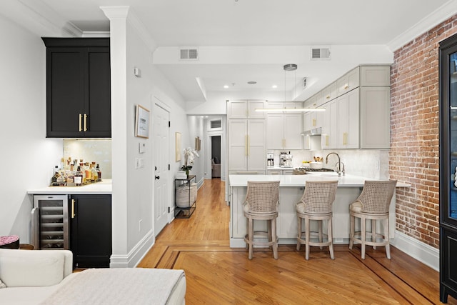 kitchen with a sink, wine cooler, light wood-type flooring, and visible vents