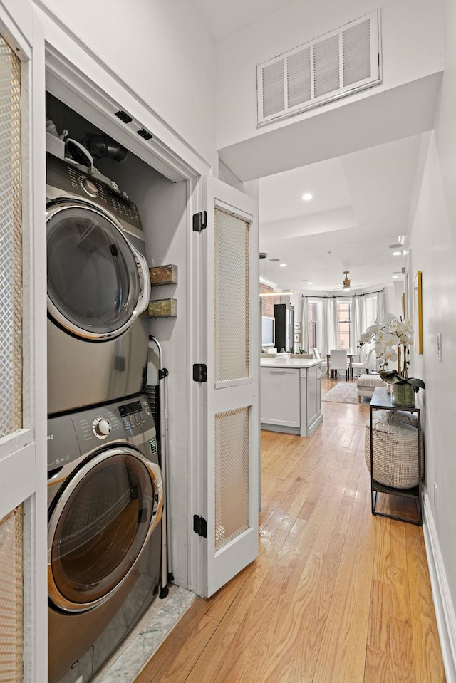 laundry area with laundry area, light wood-style flooring, stacked washer / dryer, and visible vents