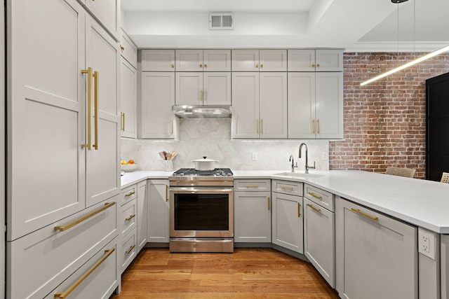 kitchen with a sink, stainless steel gas range, gray cabinets, and visible vents