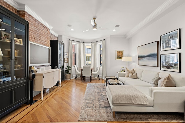 living room with light wood finished floors, brick wall, a ceiling fan, recessed lighting, and ornamental molding