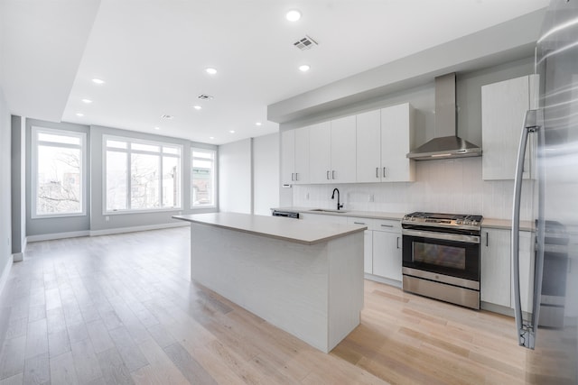 810 6th St Unit 2, Union City, NJ 07087 - kitchen with appliances with stainless steel finishes, wall chimney exhaust hood, light wood finished floors, light countertops, and decorative backsplash