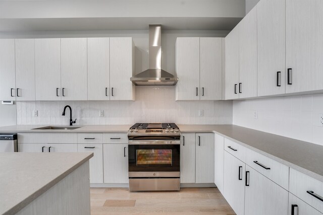810 6th St Unit 2, Union City, NJ 07087 - kitchen with appliances with stainless steel finishes, wall chimney exhaust hood, decorative backsplash, light countertops, and light wood-style flooring