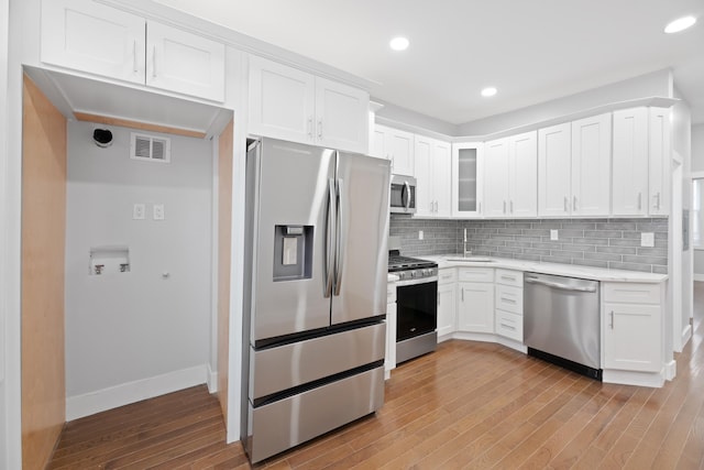 kitchen with sink, stainless steel appliances, white cabinetry, and tasteful backsplash