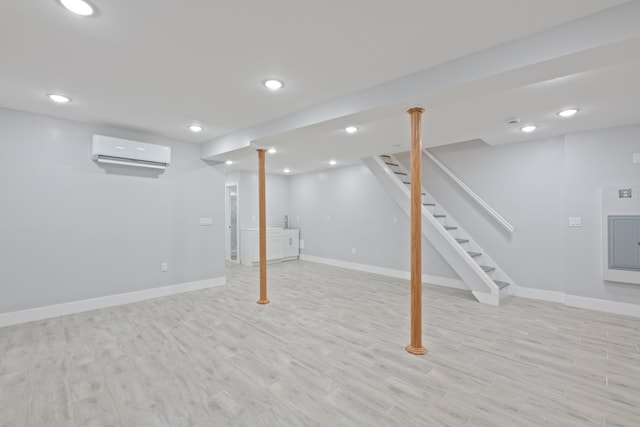 basement with light wood-type flooring and an AC wall unit