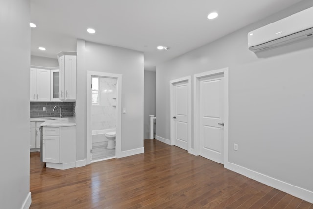 interior space with a wall mounted air conditioner, dark hardwood / wood-style flooring, and sink