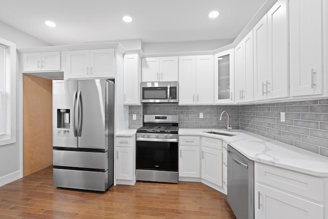 kitchen featuring sink, white cabinets, wood-type flooring, light stone countertops, and appliances with stainless steel finishes