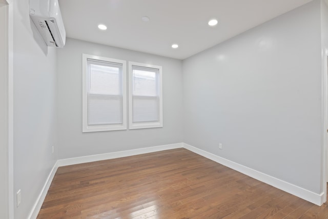 empty room featuring wood-type flooring and a wall mounted AC