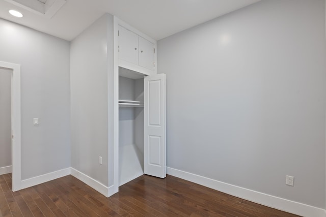 unfurnished bedroom with a closet and dark wood-type flooring