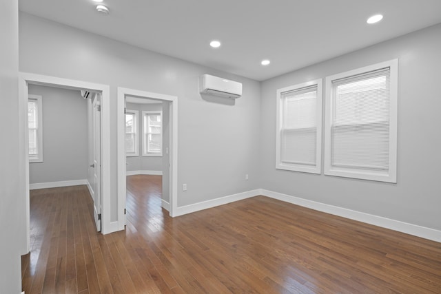 empty room with a wall unit AC and dark hardwood / wood-style floors