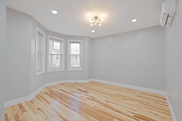 spare room with a wall mounted AC and light hardwood / wood-style floors