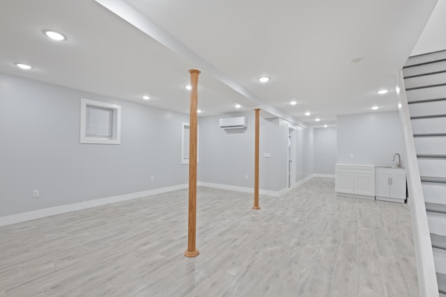 basement with sink, an AC wall unit, and light hardwood / wood-style floors